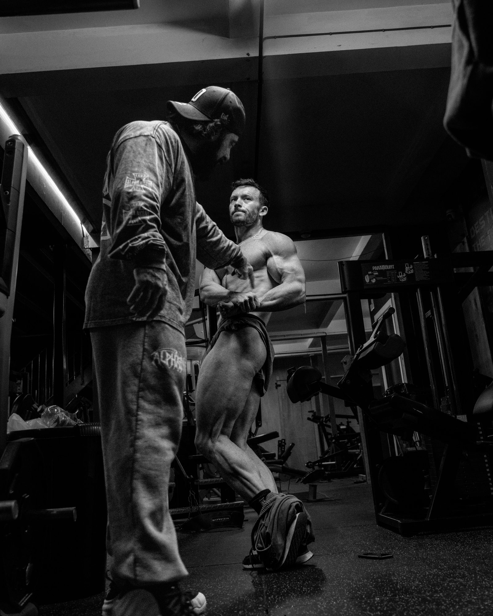 Adrian coaching a client through posing practice on the floor at Darkside Gym